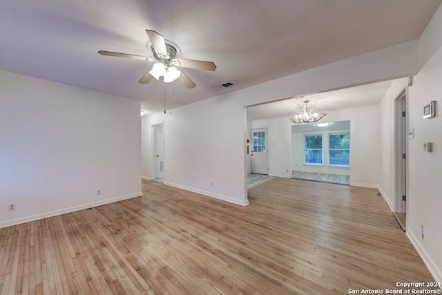 interior space with light wood-type flooring and ceiling fan with notable chandelier