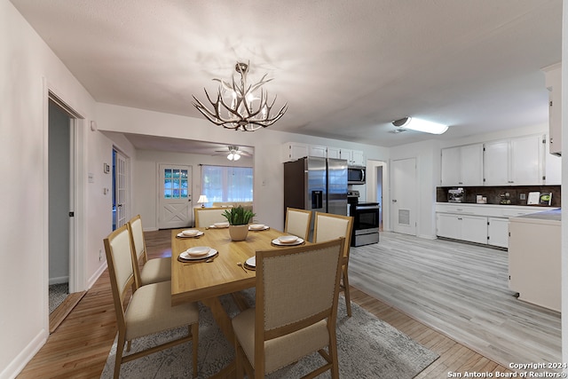 dining space with light wood-type flooring and ceiling fan with notable chandelier