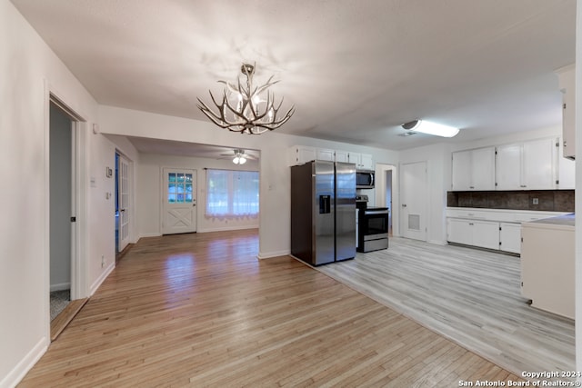 kitchen featuring ceiling fan with notable chandelier, decorative light fixtures, light hardwood / wood-style flooring, appliances with stainless steel finishes, and white cabinetry