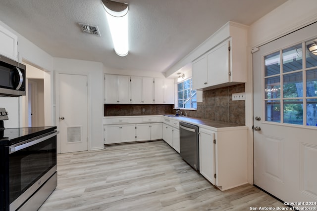 kitchen featuring light wood-type flooring, white cabinets, backsplash, and stainless steel appliances