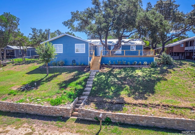 rear view of property with a wooden deck and a lawn