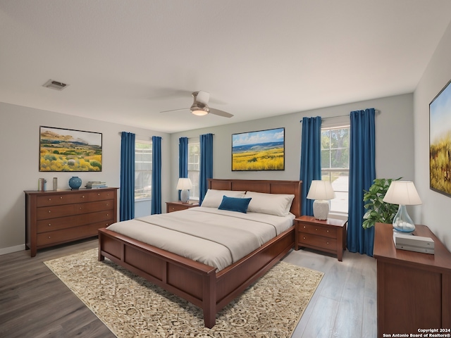 bedroom with hardwood / wood-style flooring, ceiling fan, and multiple windows