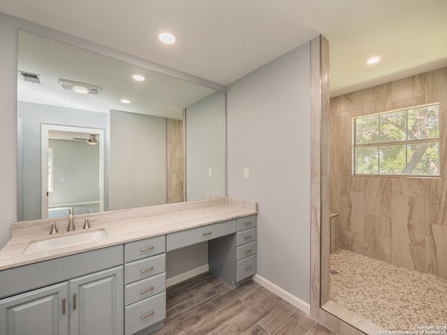 bathroom featuring wood-type flooring, a tile shower, and vanity