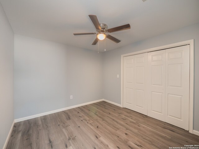 unfurnished bedroom with ceiling fan, a closet, and hardwood / wood-style flooring