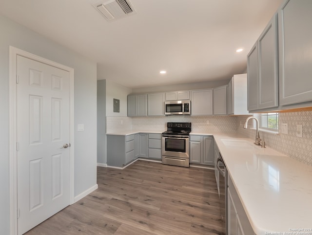 kitchen featuring light hardwood / wood-style flooring, appliances with stainless steel finishes, sink, gray cabinets, and decorative backsplash