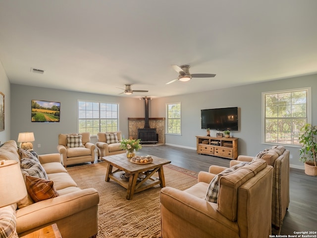 living room featuring a wood stove, ceiling fan, and hardwood / wood-style flooring