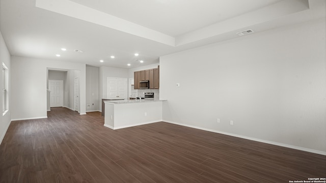 unfurnished living room featuring dark hardwood / wood-style floors and a raised ceiling