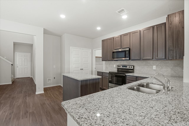 kitchen featuring light stone countertops, sink, dark wood-type flooring, kitchen peninsula, and appliances with stainless steel finishes