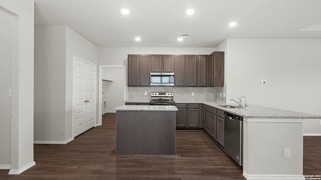 kitchen with light stone countertops, sink, a center island, stainless steel appliances, and dark hardwood / wood-style floors