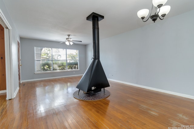 interior space with a wood stove, ceiling fan with notable chandelier, and hardwood / wood-style floors