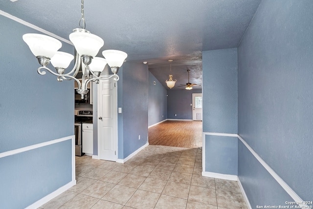 unfurnished dining area with a textured ceiling, light tile patterned flooring, and ceiling fan with notable chandelier