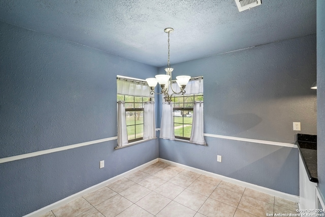 unfurnished dining area with tile patterned floors, a chandelier, and a textured ceiling