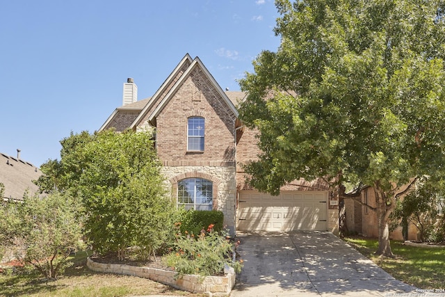 view of front of property with stone siding, a chimney, brick siding, and concrete driveway