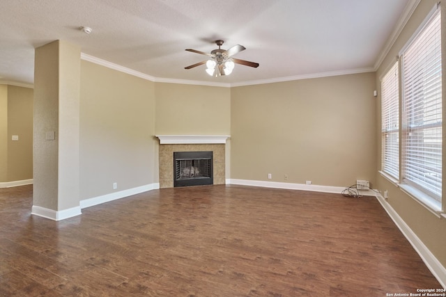unfurnished living room featuring dark wood finished floors, a tile fireplace, crown molding, baseboards, and ceiling fan