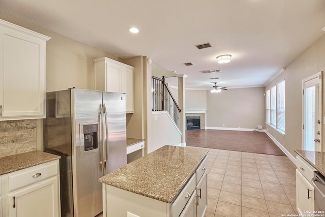 kitchen with light stone counters, white cabinetry, stainless steel appliances, and ceiling fan