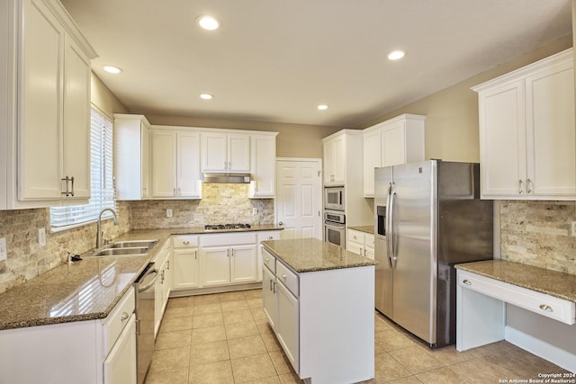 kitchen featuring tasteful backsplash, dark stone countertops, a sink, stainless steel appliances, and under cabinet range hood