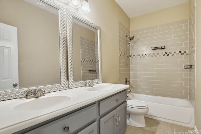 full bathroom with tiled shower / bath, vanity, and toilet