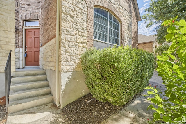 doorway to property featuring brick siding and stone siding