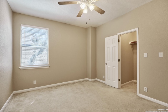 unfurnished room featuring a ceiling fan, baseboards, and light carpet
