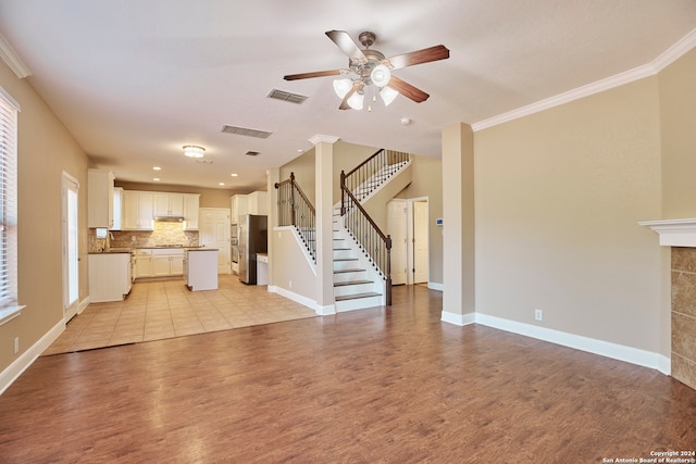 unfurnished living room with ornamental molding, a fireplace, light hardwood / wood-style floors, and ceiling fan