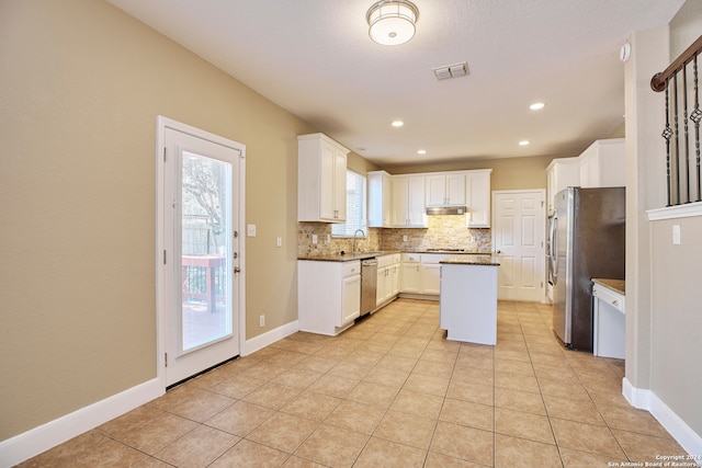 kitchen featuring a kitchen island, appliances with stainless steel finishes, white cabinetry, sink, and backsplash