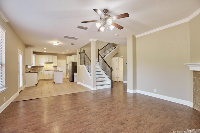 unfurnished living room featuring light wood finished floors, ornamental molding, visible vents, and ceiling fan