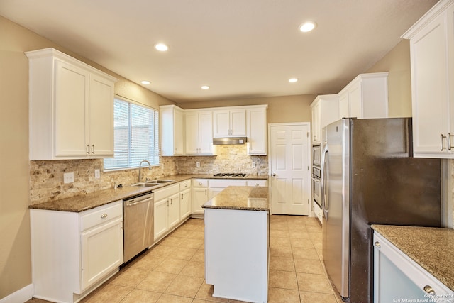 kitchen featuring appliances with stainless steel finishes, a center island, sink, and dark stone counters