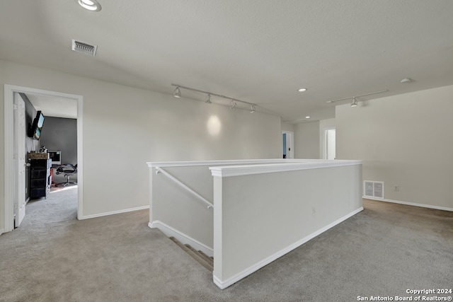 hallway with rail lighting and carpet floors