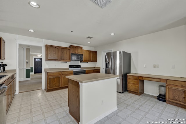 kitchen with appliances with stainless steel finishes, built in desk, and a kitchen island