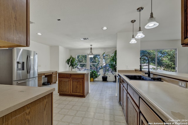 kitchen with sink, pendant lighting, and stainless steel fridge