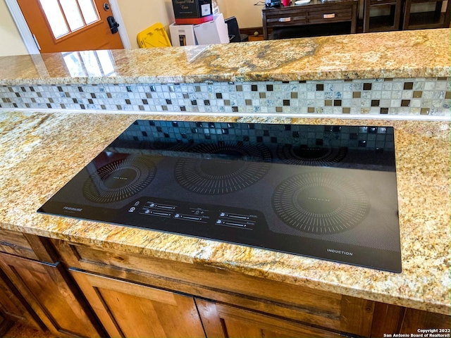 details featuring black electric stovetop and light stone counters