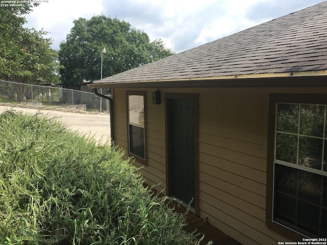 view of home's exterior featuring roof with shingles and fence