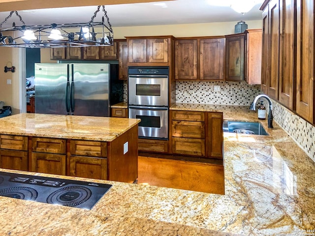 kitchen with a center island, a sink, tasteful backsplash, light stone countertops, and appliances with stainless steel finishes