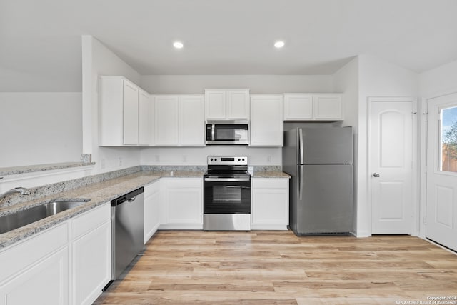 kitchen featuring light hardwood / wood-style flooring, light stone counters, appliances with stainless steel finishes, and white cabinets