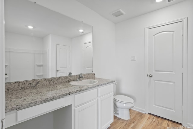 bathroom with vanity, toilet, hardwood / wood-style flooring, and a shower