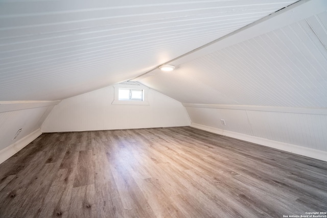 additional living space featuring lofted ceiling, wood walls, and wood-type flooring