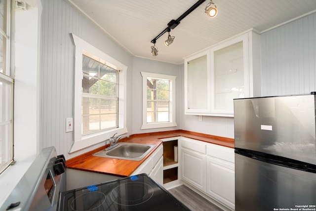 kitchen featuring crown molding, stainless steel refrigerator, sink, white cabinetry, and rail lighting