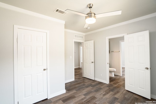 unfurnished bedroom featuring crown molding, ensuite bath, ceiling fan, a closet, and dark wood-type flooring