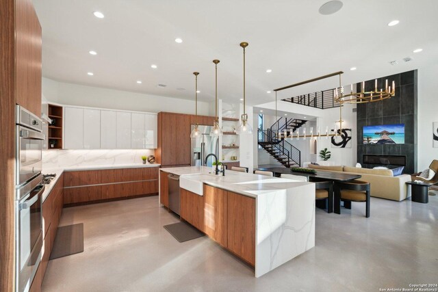 kitchen with white cabinets, hanging light fixtures, a notable chandelier, sink, and a spacious island