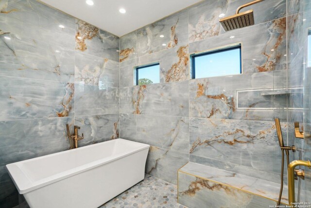 bathroom with shower with separate bathtub and tile walls