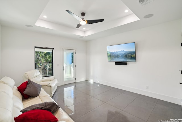 unfurnished living room with a tray ceiling, ceiling fan, and tile patterned flooring