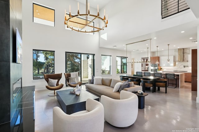 living room featuring a high ceiling, a chandelier, and concrete floors