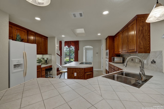 kitchen featuring tile countertops, white appliances, sink, kitchen peninsula, and pendant lighting