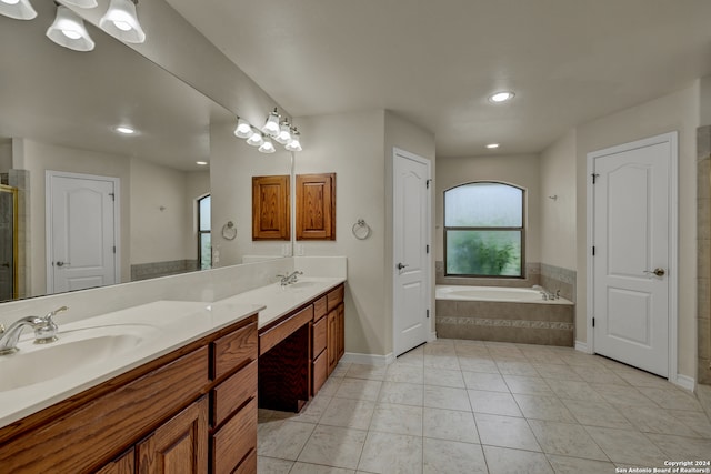 bathroom featuring a healthy amount of sunlight, tile patterned flooring, tiled bath, and vanity