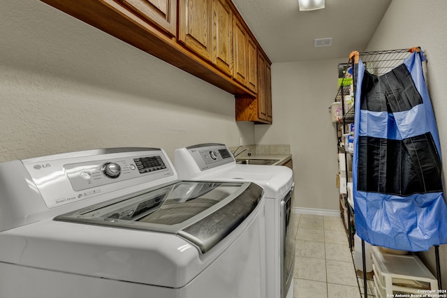 laundry room featuring light tile patterned flooring, cabinets, independent washer and dryer, and sink