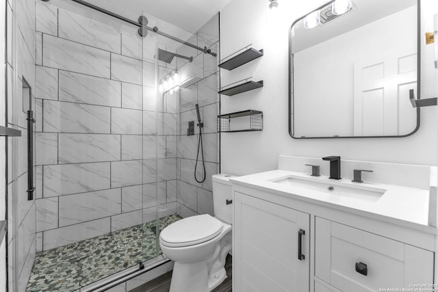 bathroom with tiled shower, vanity, and toilet