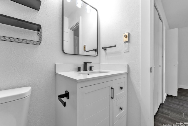 bathroom with hardwood / wood-style flooring, vanity, and toilet