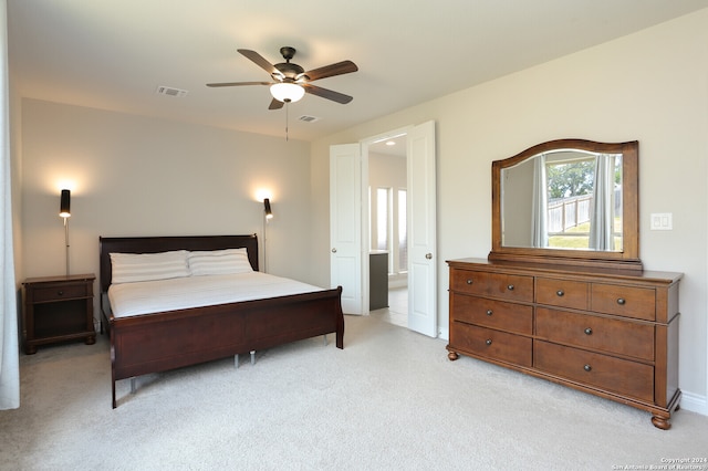 bedroom with light colored carpet, ensuite bathroom, and ceiling fan