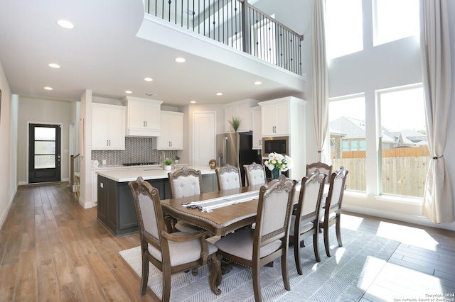 dining space featuring a high ceiling and light hardwood / wood-style floors