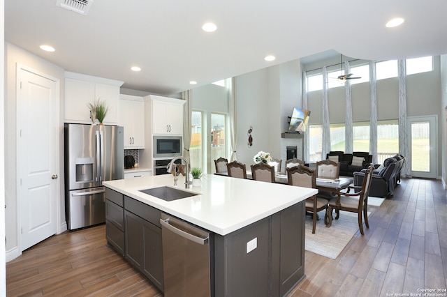 kitchen with appliances with stainless steel finishes, an island with sink, sink, ceiling fan, and white cabinets